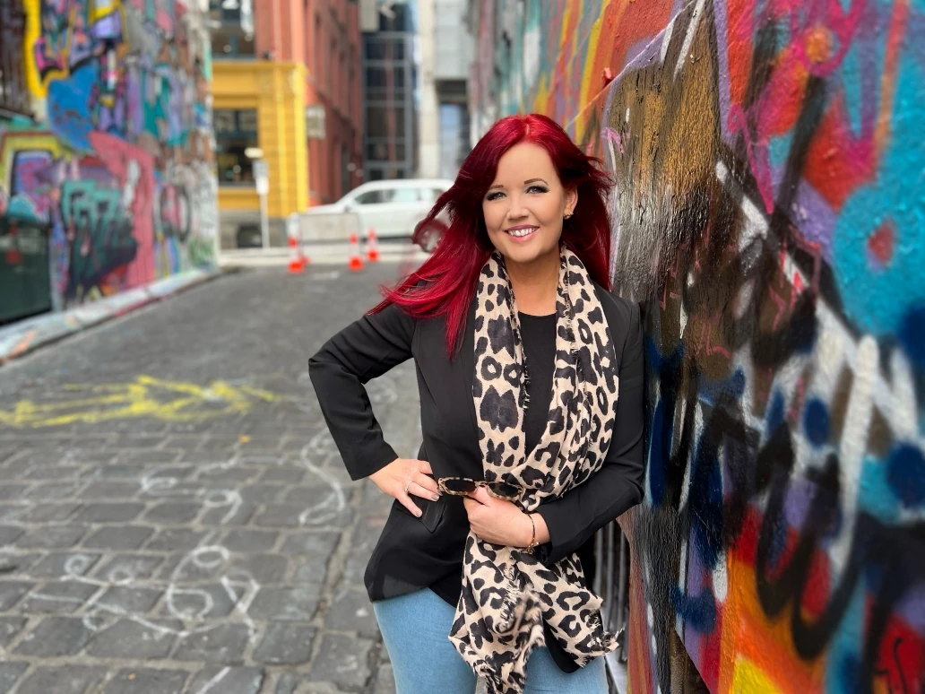 Sam Lovegrove smiling in a colourful street-art laneway